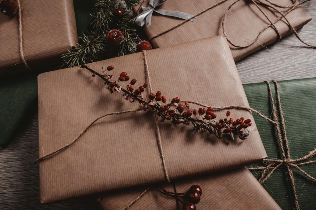 Rustic brown paper Christmas gifts with twine and red berry accents on wooden background.