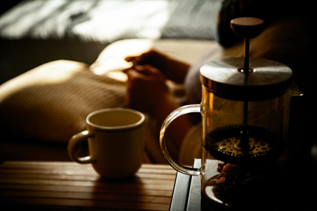 Warm and cozy morning scene featuring a French press and coffee cup indoors.